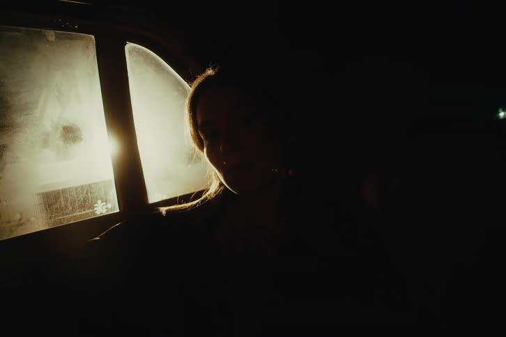 Silhouette of a womans face sitting in the back seat of a car at night