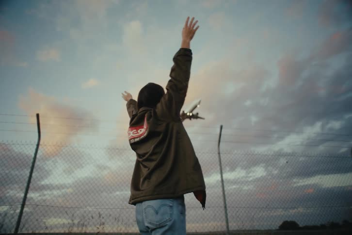 Woman opening her arms upwards while a plane is landing