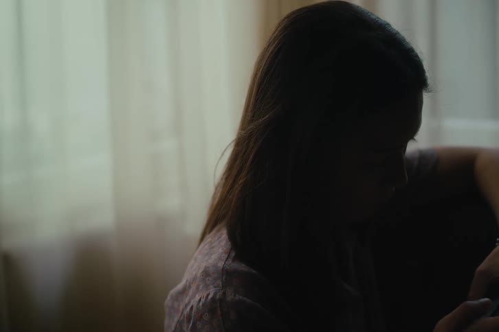 Silhouette of the face of a woman sitting concentrated using a smartphone