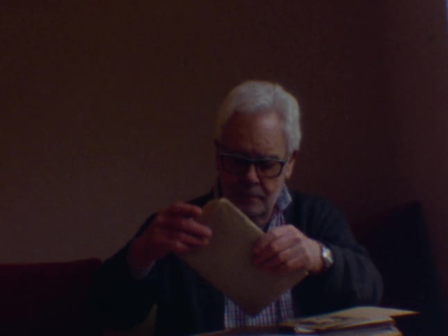 An old man wearing glasses sorts through various envelopes