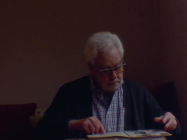 Elderly man sitting looking at a photo album