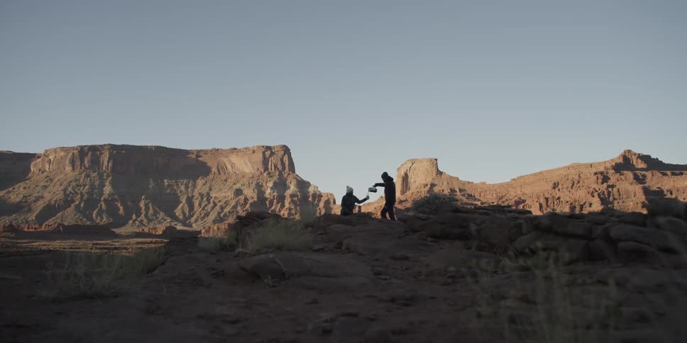 Person pouring a beverage in a wilderness area surrounded by large rock formations