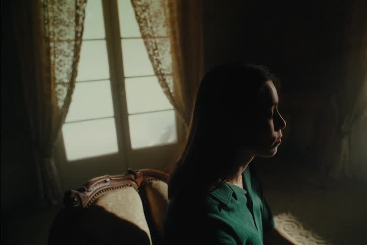 Woman sits in dimly lit room typing