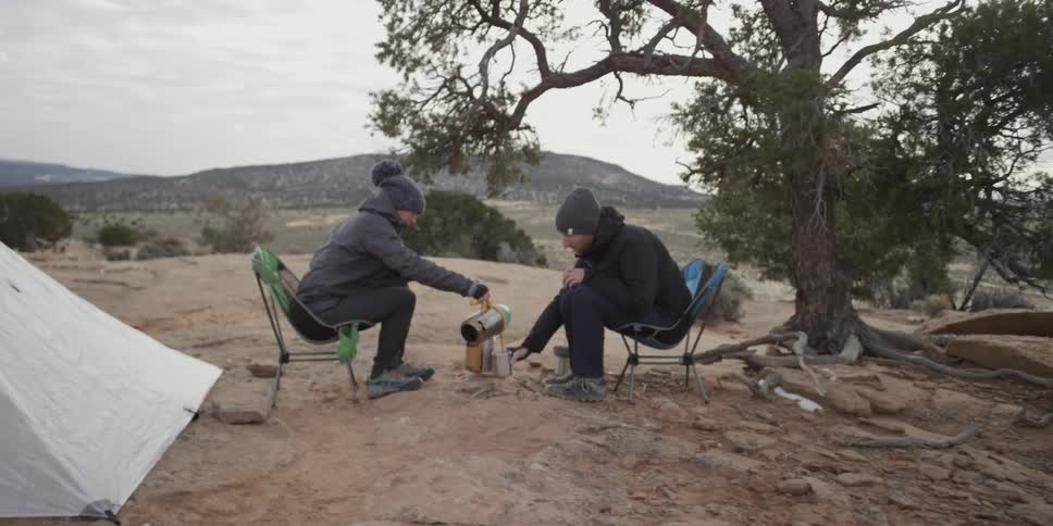 A man pouring hot water into a cup at a campsite