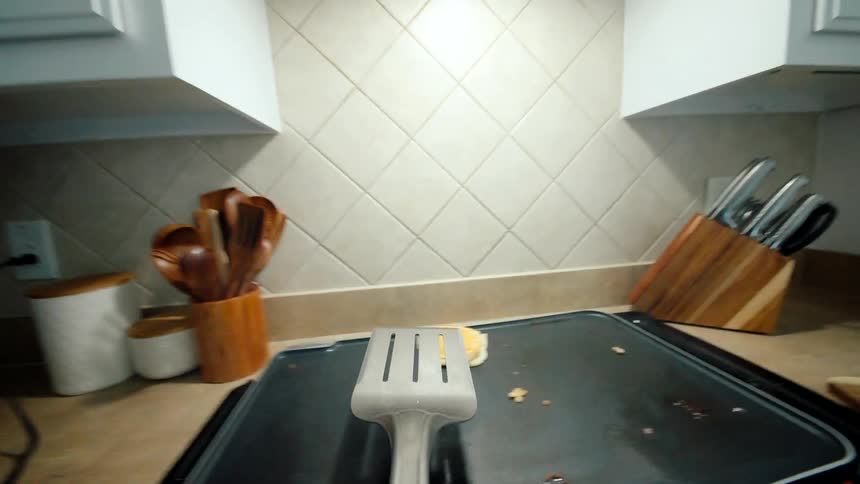 Point of view of a spatula throwing a fried egg on top of the stove