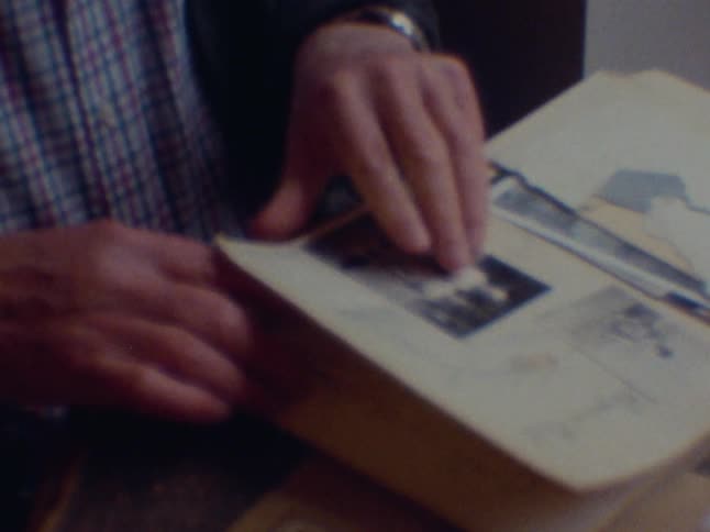 An elderly man looks through old photos and journals