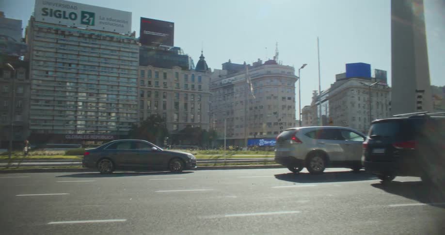 Traffic moves past a large obelisk in a city