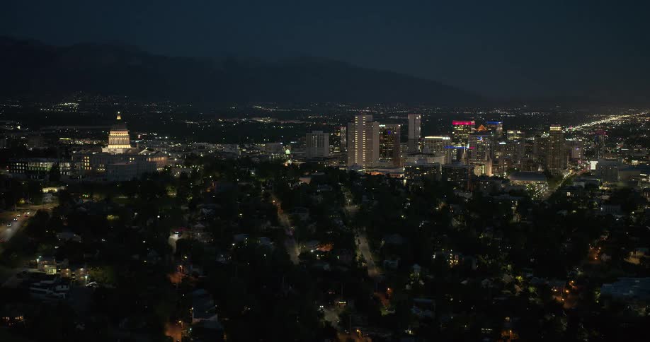 An aerial view of a metropolitan city with one part without lights and the other with taller buildings with lights