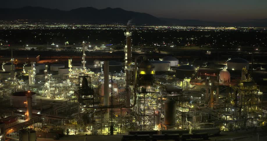 A large refinery sits on the outskirts of a city that sits in a large mountain valley
