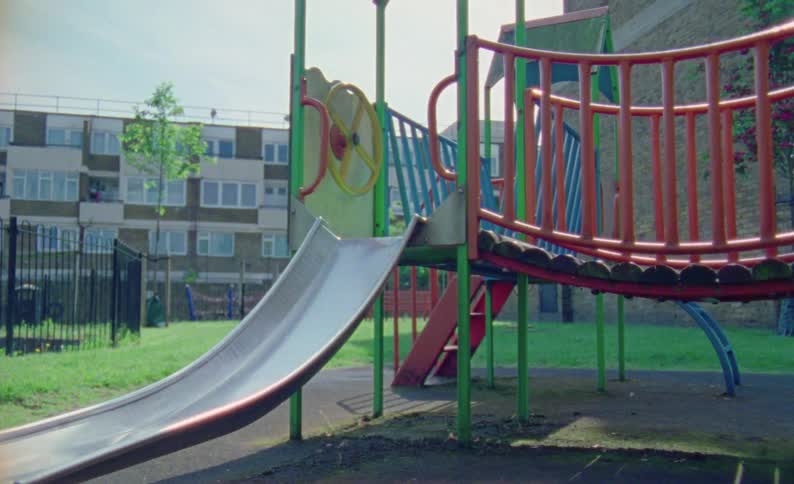 Toy with slide in a park and urban buildings in the background