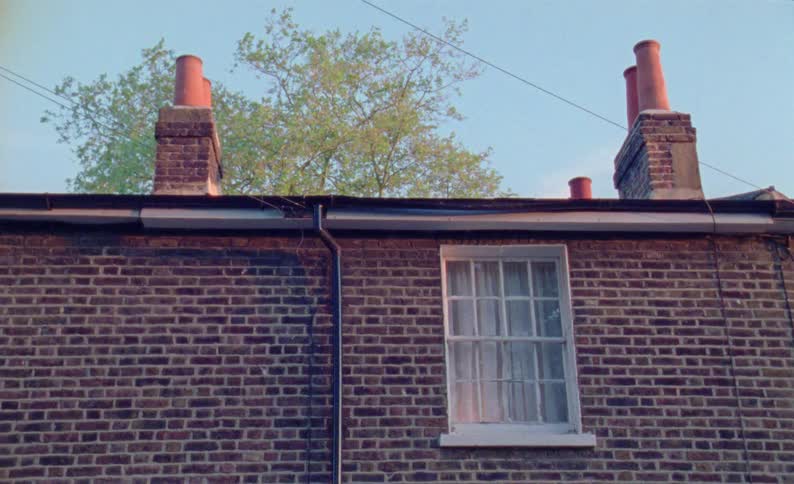 A brick building with two visible chimneys stands against a blue morning sky