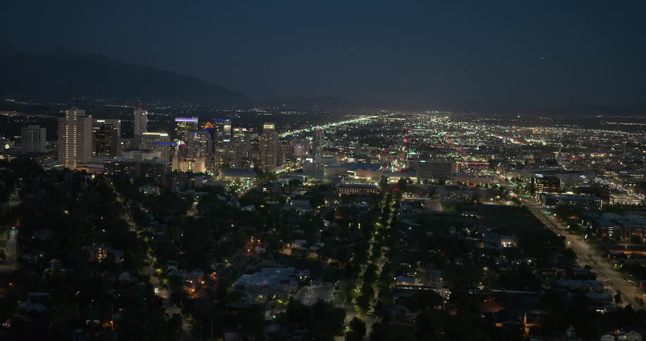 A metropolitan city with some of the low houses in the dark and the tall buildings have lights on