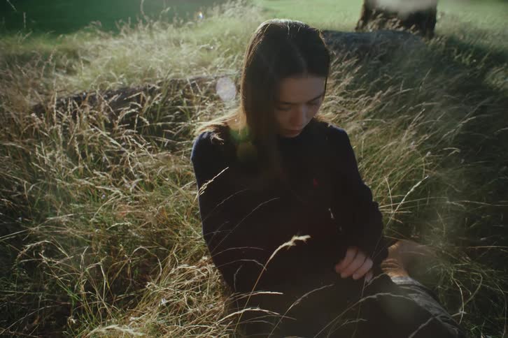 Woman sitting in a natural environment with grass and trees