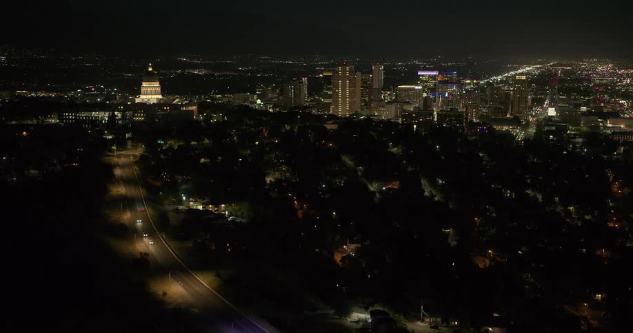 An aerial view of a metropolitan city that is dark and there is a street with some cars passing by