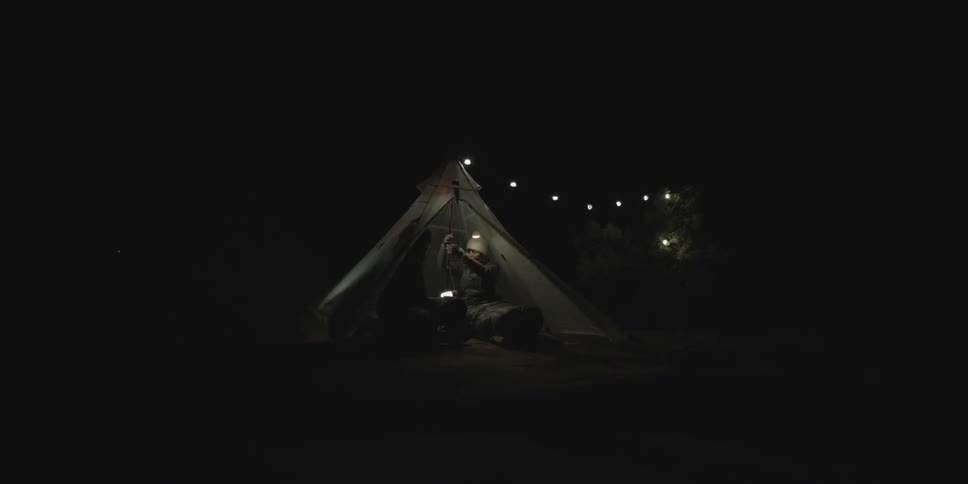 Two people sitting in a tent after dark