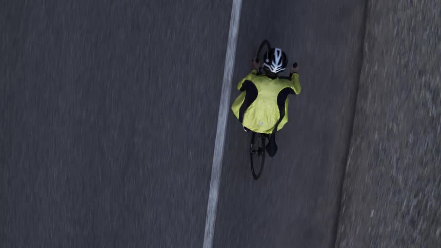 Man adjusting jacket while riding bicycle on a highway