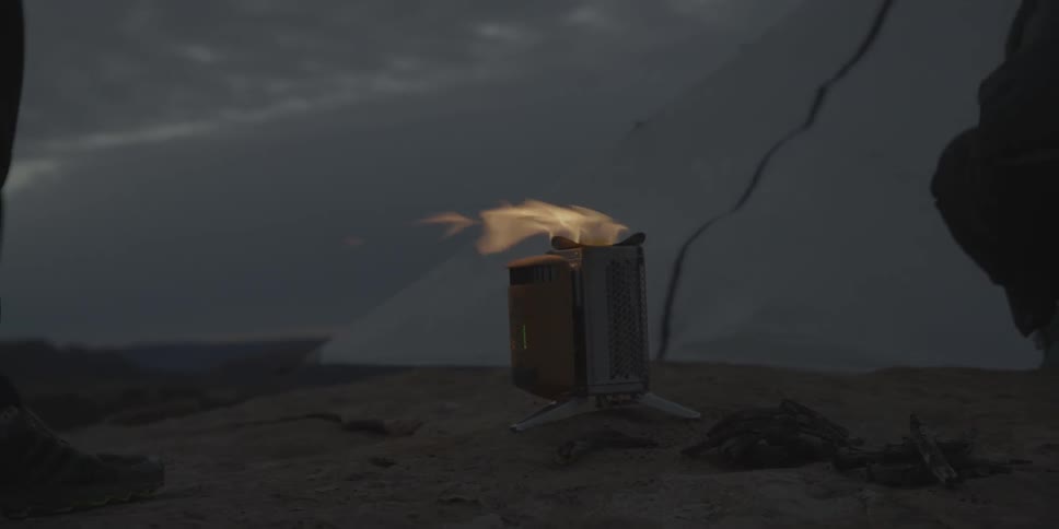 Person walking past a fire burning in a small container