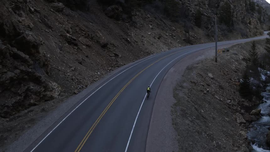 Aerial view of a cyclist pedaling along a mountainous highway