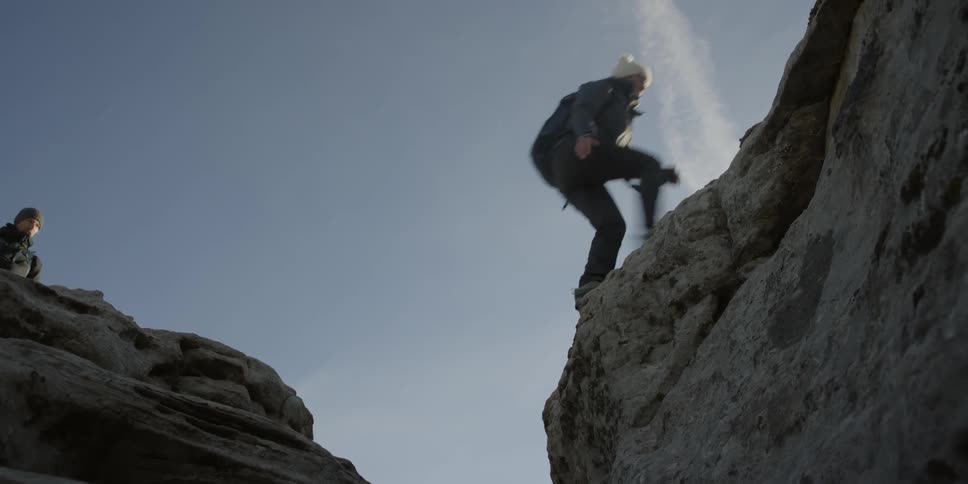 Hikers hop over a rocky opening
