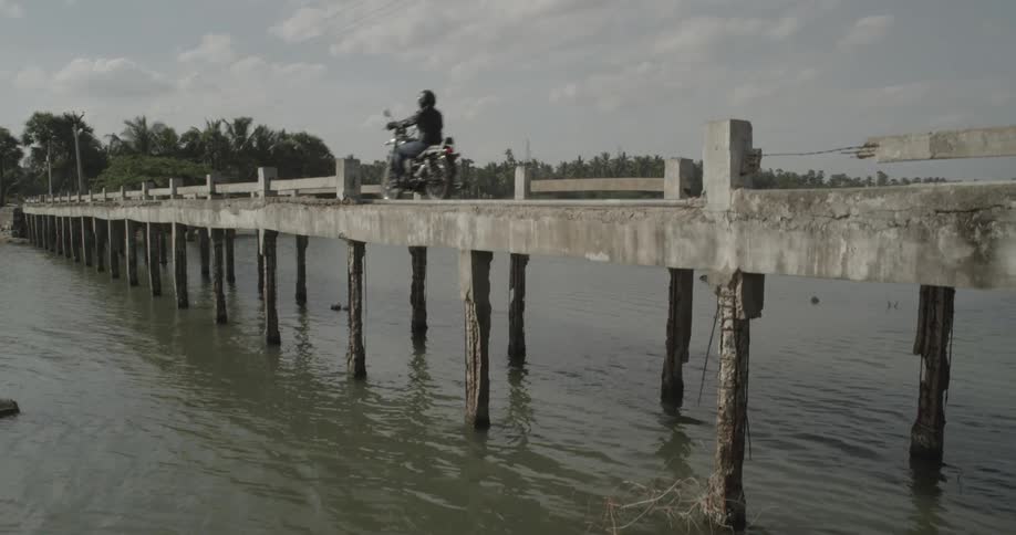 Motorcycles race across a wooden bridge