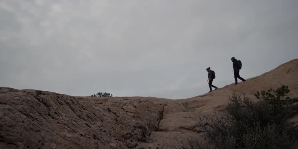A man and woman hike on a cloudy day