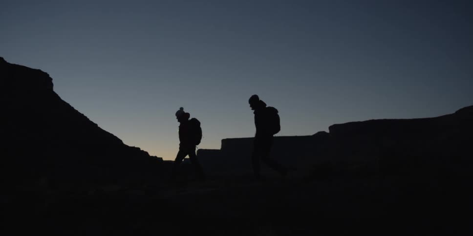 Silhouette of two hikers walking a trail at sunset