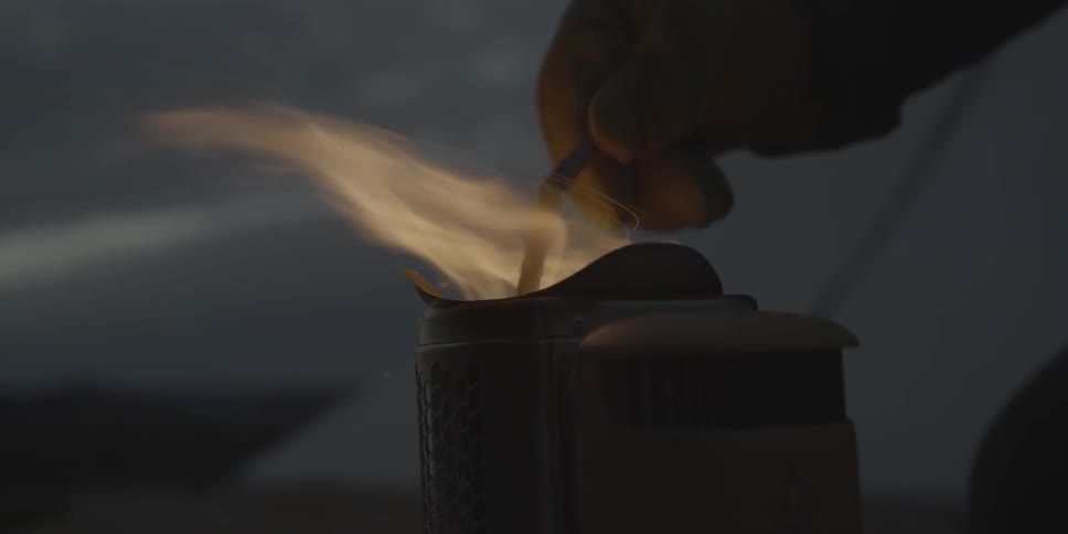 A dirty hand stirs a very hot flame at night
