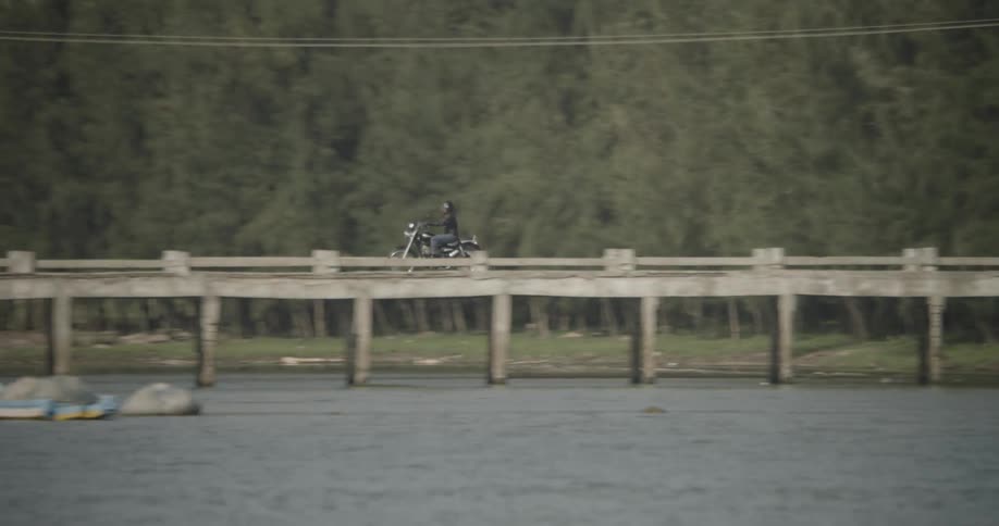Motorcyclist riding across a bridge