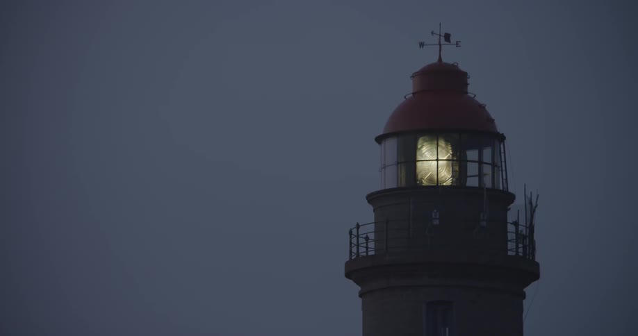 Beacon turning from a lighthouse tower against a  dark sky