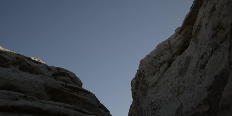 Hiker jumping across a crevice along his trail