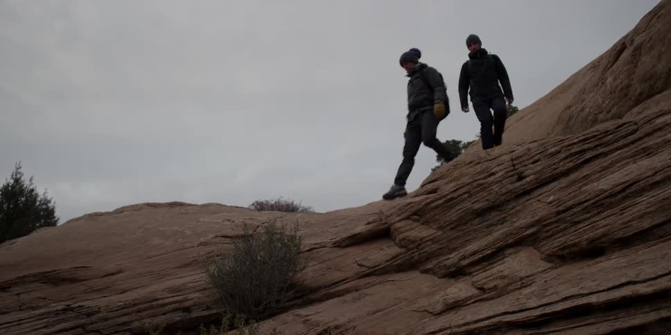 Two people walk on the rocks above on a cloudy day