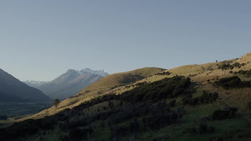 A scenic mountain landscape with sunlight casting shadows on the hills and peaks