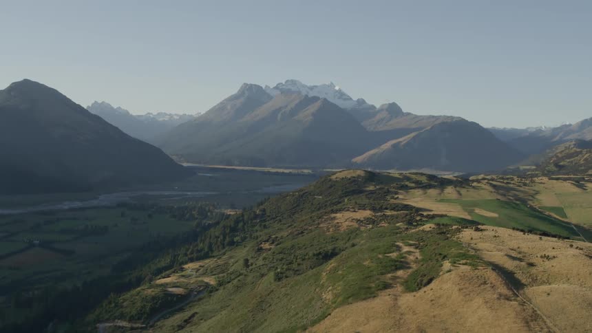 A breathtaking view of a mountainous landscape with green valleys and rugged peaks under a clear sky