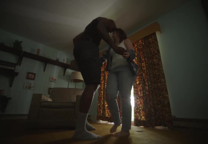 A man and a woman dance together in the living room of a house