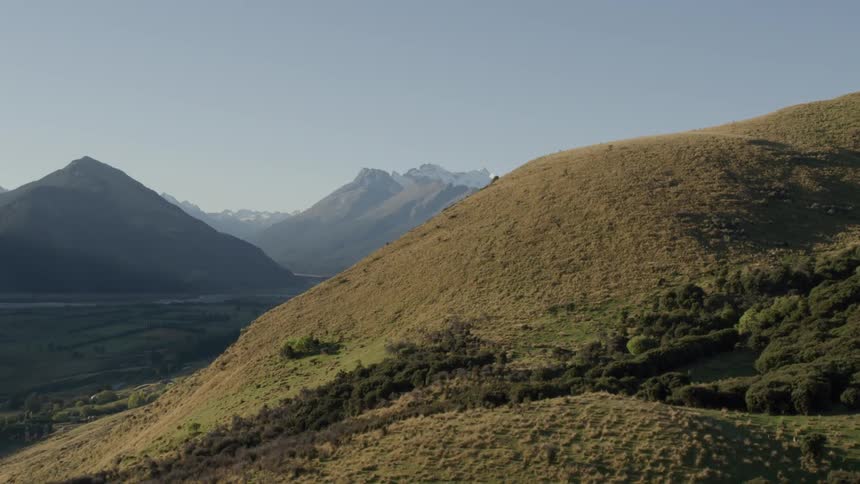 Aerial panorama of mountain ranges on a clear day with deer on tussock grass