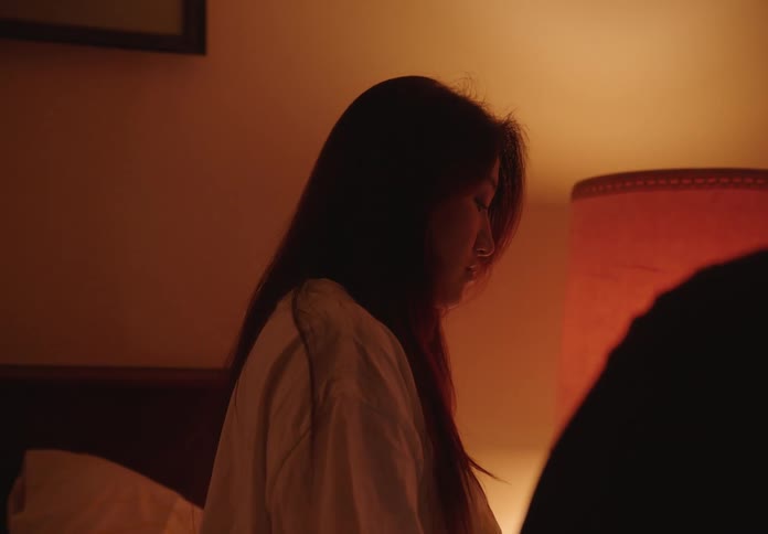 Woman sitting on the bed with a scared facial expression