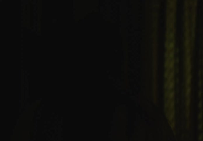 Close up of the silhouette of a woman pacing around on a dimly lit room