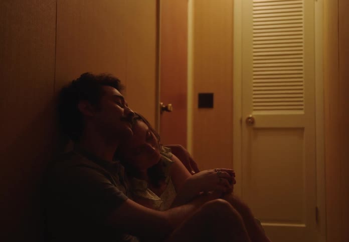 A man and a woman sit together in the hallway of a house