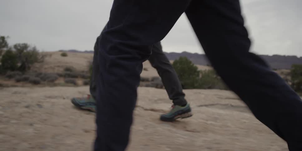 Couple hiking through a barren land as seen from the waist down