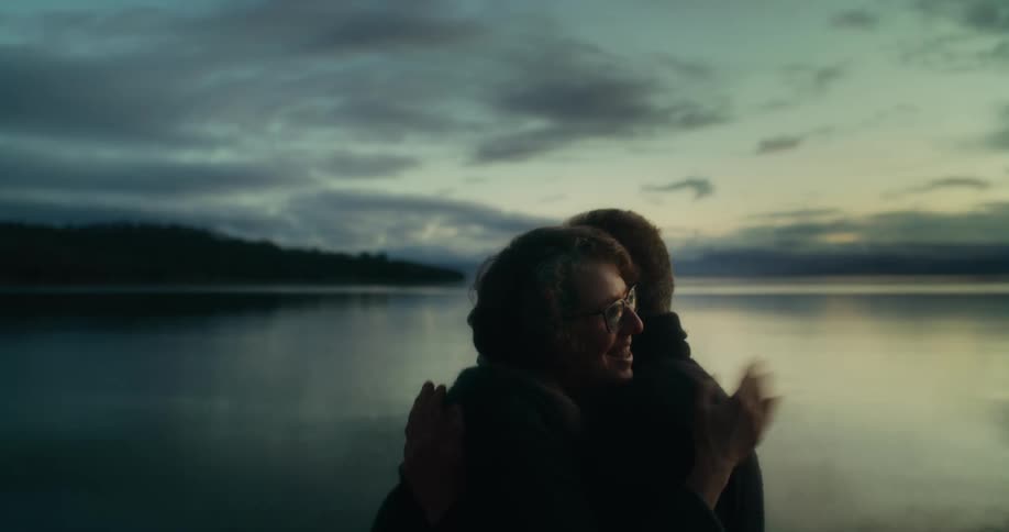One man one woman couple next to a lake hugging and giving a kiss