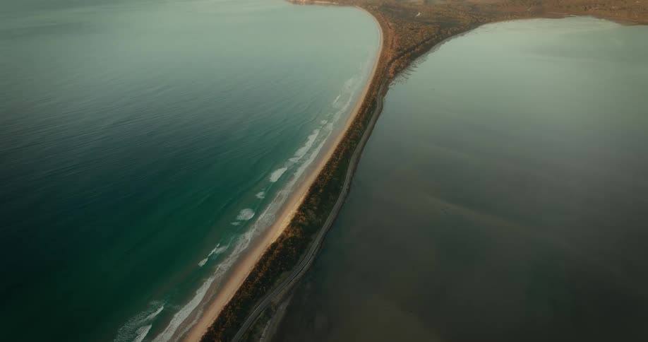 Aerial view of a land bridge with a highway between two bodies of water in the late afternoon