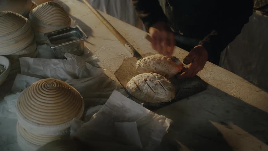 Man making cuts in bread dough and putting it to bake