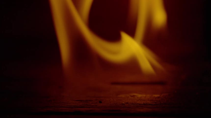 Close up of flames burning a flat wooden surface at night