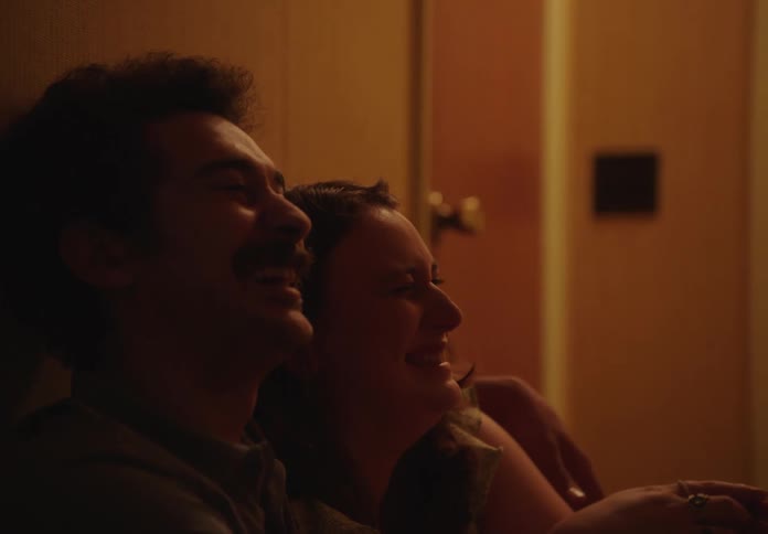 Man and woman hugging each other sitting in a narrow hallway smiling