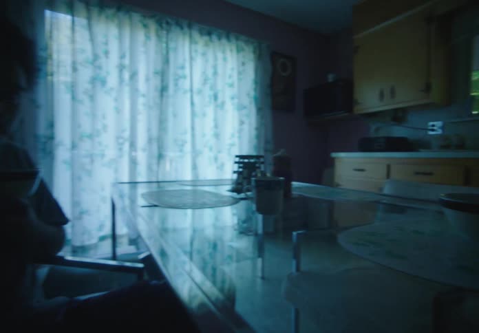 A couple eating breakfast at a table in a dimly lit kitchen