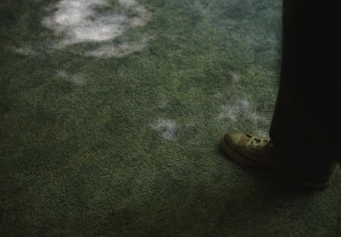 Feet of a person walking back and forth in a field with green grass