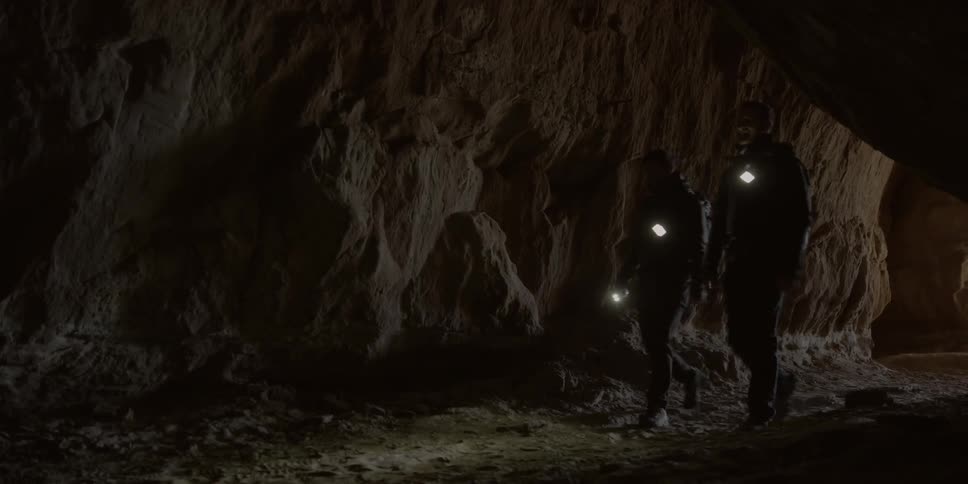 Two people enter a dark cave together