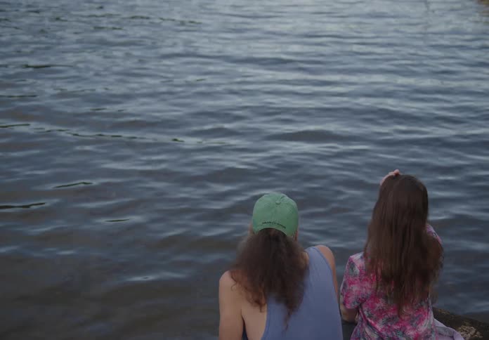 Two friends talk by the water