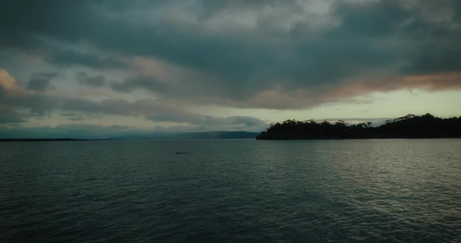Vast body of water with a cloudy sky above and a line of land in the background