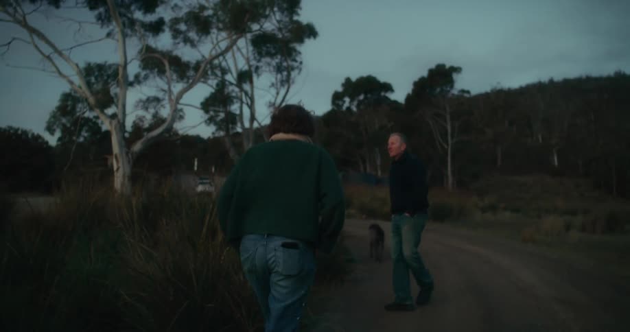 Two people and a dog walking in a natural environment